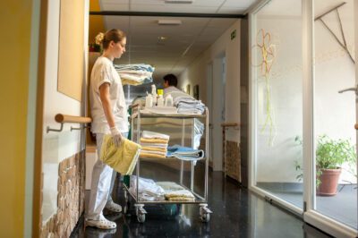 verpleegkundige staat op de gang met een kar vol met handdoeken
